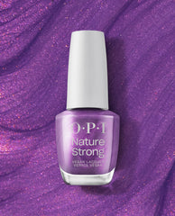 OPI Achieve Grapeness Nature Strong Vegan Nail Lacquer bottle stands upright, showing a shimmery grape-purple fall nail color against a sparkling purple textured background.