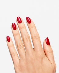 Hand displays glossy red shimmer manicure using OPI RapiDry Ring the Alarm, a bold shade for fall nail colors, on short rounded nails against a clean white background.