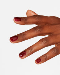 Hand with neatly manicured nails painted in Como se Llama? deep burgundy OPI nail polish, showing glossy nail lacquer finish against a clean white background for a modern salon-quality look.