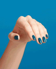 Hand with neatly manicured nails flexing to showcase Drama at La Scala, a deep teal OPI nail polish nail lacquer, against a solid bright blue background, highlighting the glossy salon-quality finish for stylish US nail looks.
