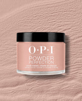 OPI France-y Seeing You Here dipping powder jar sits on a textured blush pink surface, showing a soft rosy nude shade with a glossy black lid for fall nail colors.