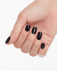 Hand displays a glossy near-black manicure with OPI Lincoln Park After Dark nail lacquer, a deep vampy shade for fall nail colors, on short rounded nails against a white background.