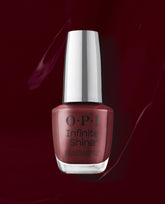 OPI Infinite Shine Raisin' The Bar nail polish bottle stands against a glossy deep burgundy background, showcasing a warm raisin-red shade ideal for fall nail colors.