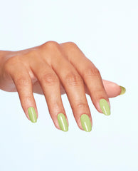 Manicured hand displays OPI Clear Your Cash nail lacquer, a glossy pastel lime green nail polish on medium-length oval nails, fanned outward against a clean light-blue studio background for fresh spring nail colors.