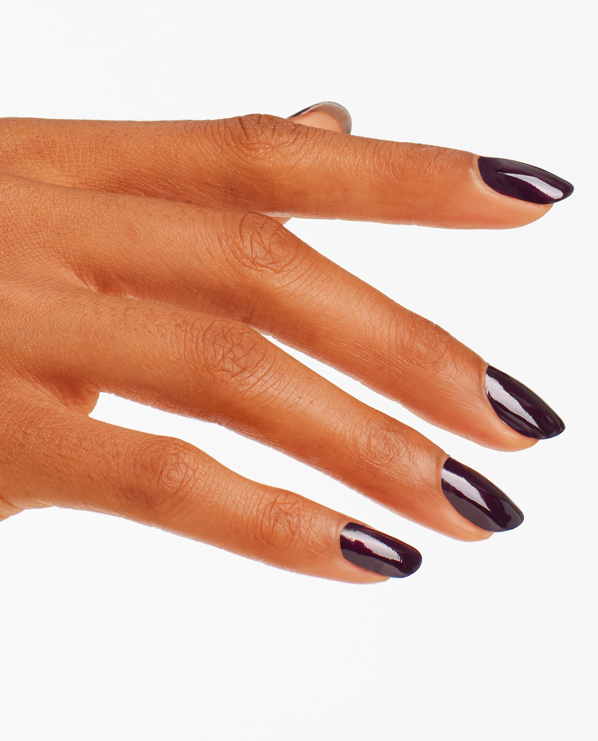 Hand modeling OPI Black Cherry Chutney nail lacquer, a glossy deep plum-black manicure on almond-shaped nails against a white background, ideal for fall nail colors.