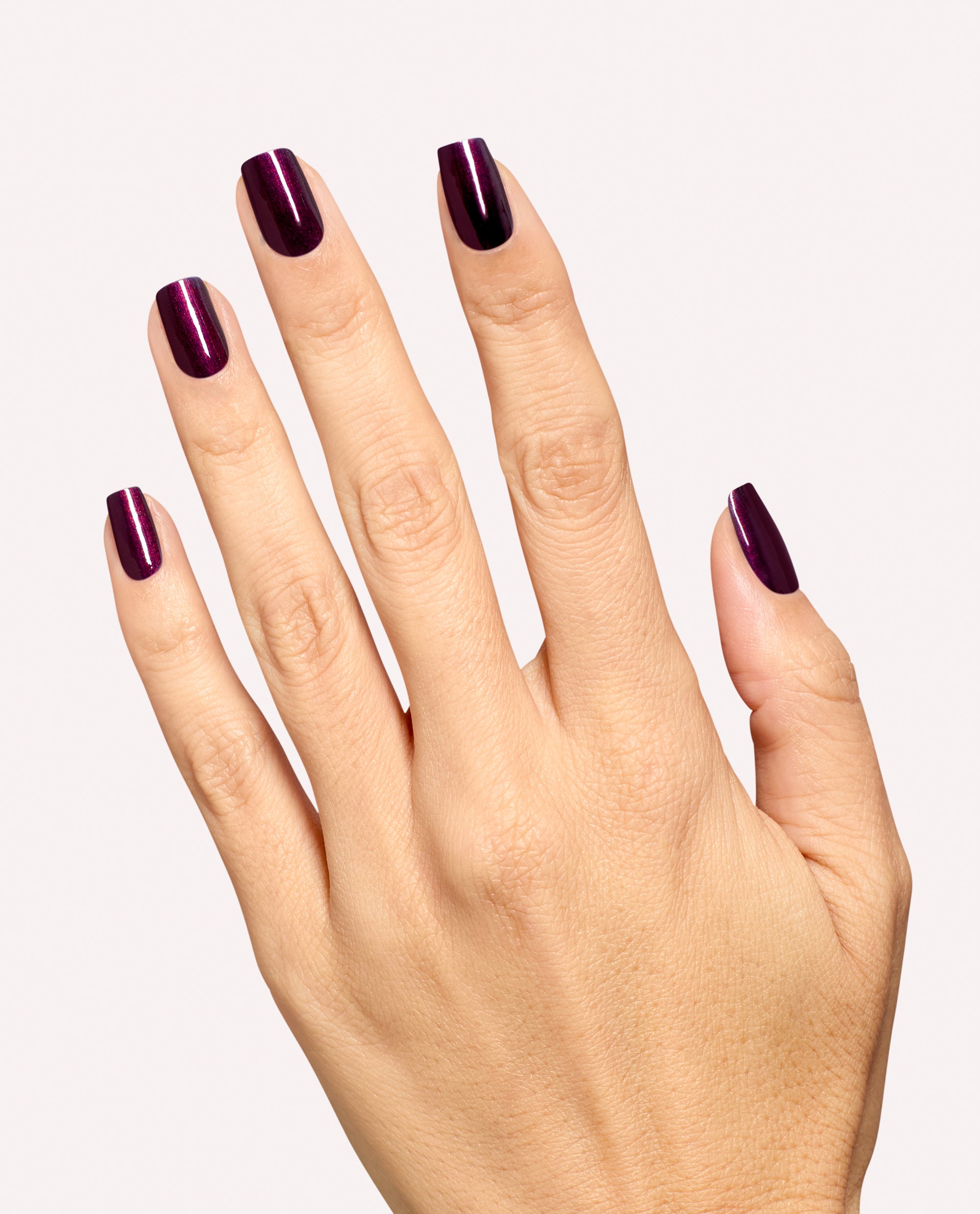 Hand modeling glossy deep plum shimmer nails painted with OPI Every Month is Oktoberfest nail lacquer, a rich shade for fall nail colors, on a clean light background.