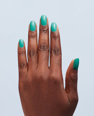 Manicured hand showcasing I’m Yacht Leaving Gel Nail Polish, a glossy teal green nail polish ideal for spring nail colors for OPI lovers, against a light blue studio background.