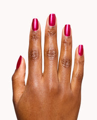 Manicured hand displays glossy metallic fuchsia nails in OPI It's All Greek to Me dipping powder, a bold choice for fall nail colors, against a clean white background.