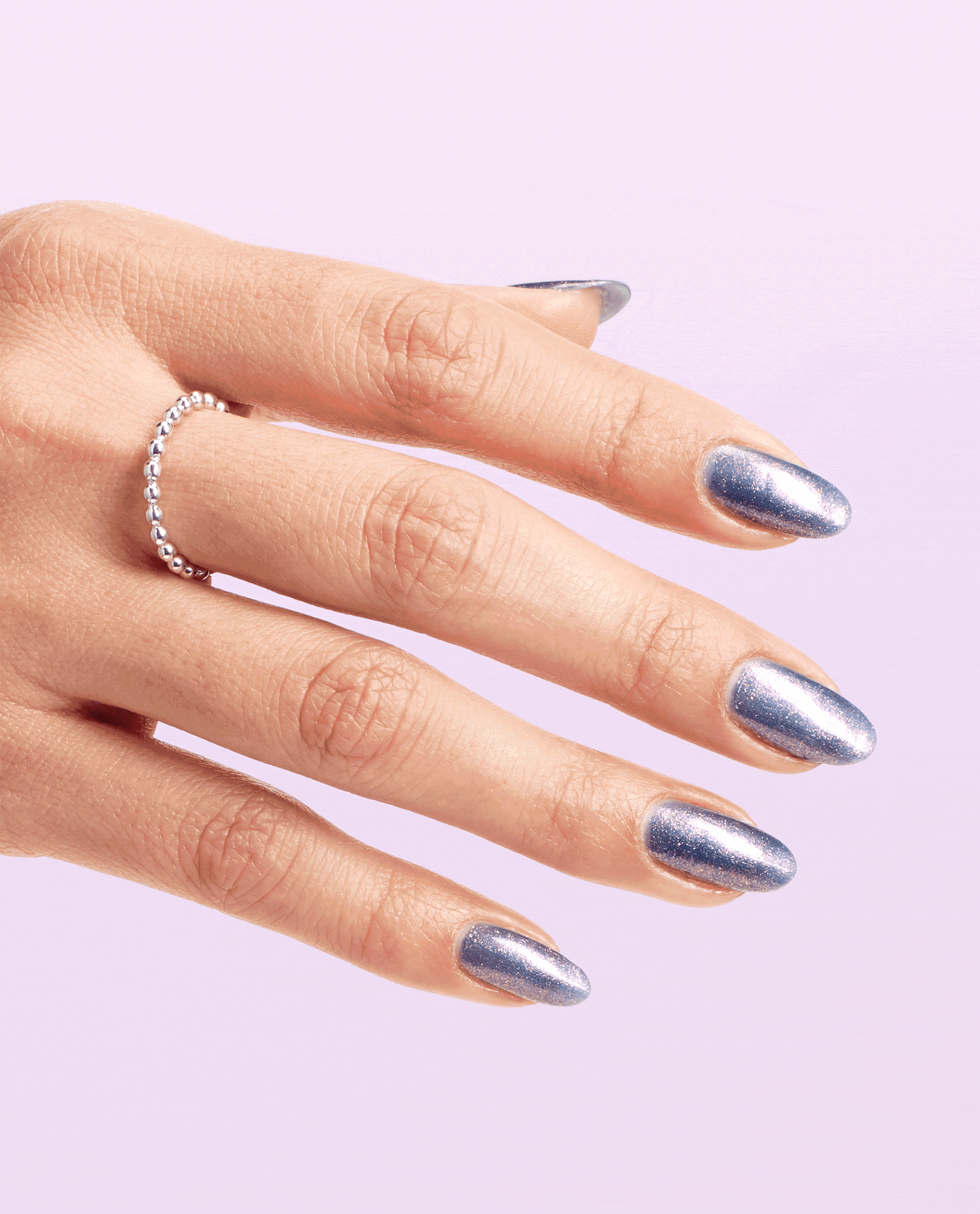 Hand with medium-length oval nails painted in Leonardo's Model Color, a shimmering icy blue OPI nail polish, slowly turning to show glossy coverage against a soft pastel pink background, with a delicate silver beaded ring on one finger.