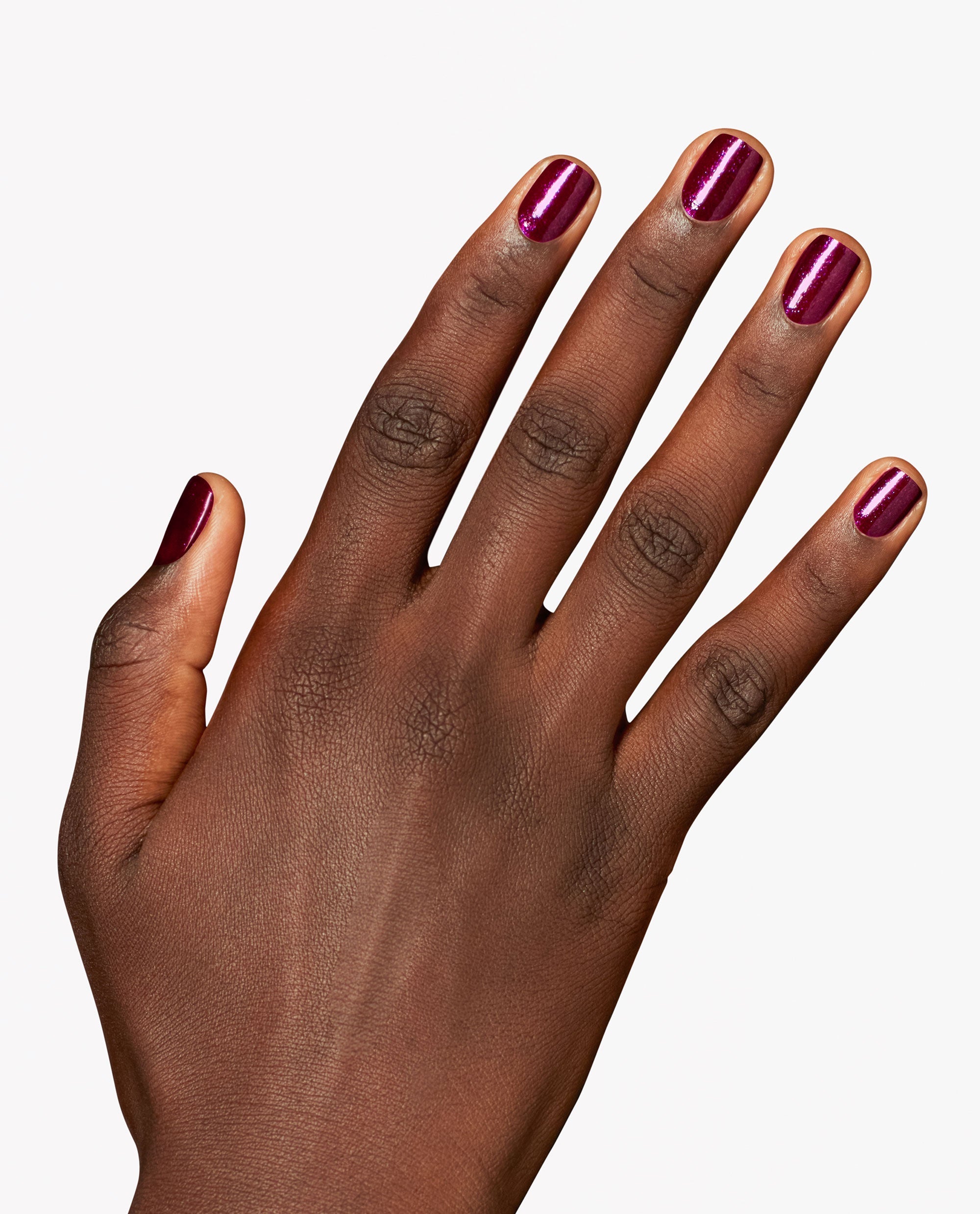 Hand modeling OPI Lincoln Park After Brunch nail lacquer, a glossy deep berry-purple shimmer manicure on short rounded nails against a clean white background.