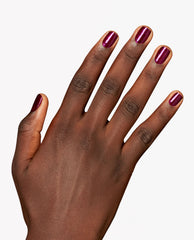 Hand modeling OPI Lincoln Park After Brunch nail lacquer, a glossy deep berry-purple shimmer manicure on short rounded nails against a clean white background.