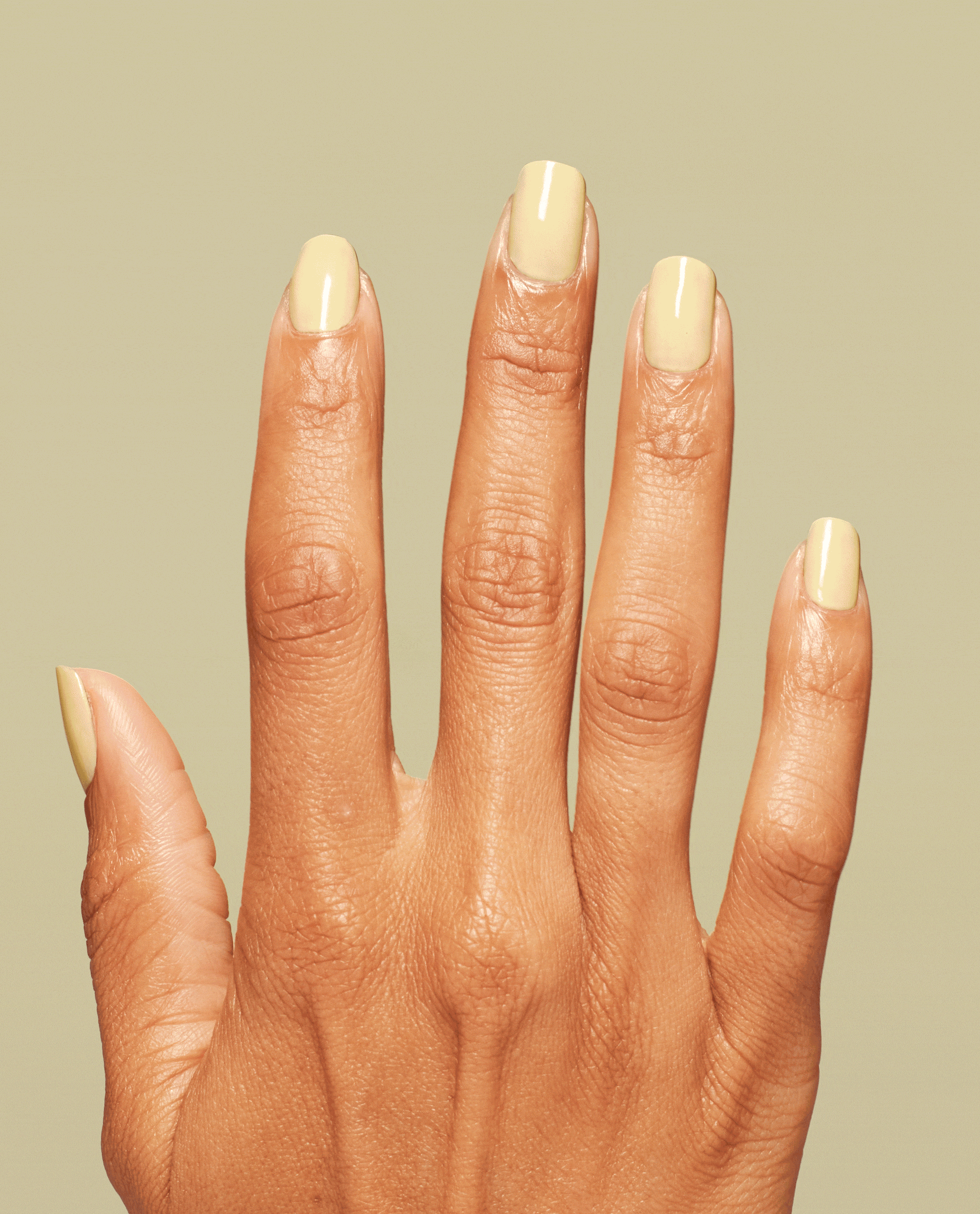 Hand showing glossy pale yellow OPI Buttafly Nail Lacquer on short rounded nails against a soft yellow background.