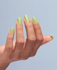 Manicured hand showcases glossy pastel‑lime nails painted with OPI Summer Monday-Fridays gel nail polish, a vibrant green nail polish perfect for spring nail colors, shown in close-up against a soft blue background.