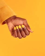 Hand shows glossy sunshine-yellow manicure in OPI Sun, Sea, and Sand in My Pants Nail Lacquer, fingers curled inward against a bright golden backdrop with a mustard knit sleeve, highlighting top spring nail colors and spring nail trends.