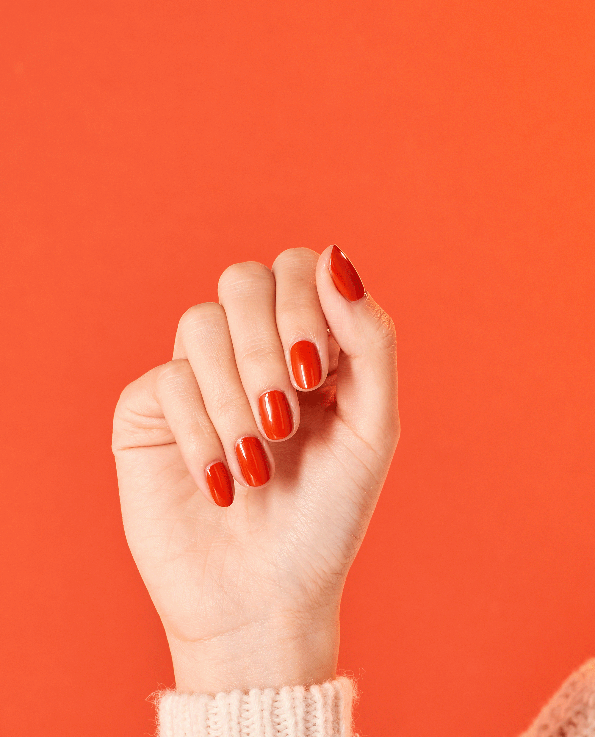 Hand with medium-length nails painted in Suzi Needs a Loch-smith OPI nail polish, a glossy burnt orange nail lacquer, held against a matching orange background for a bold, monochromatic manicure look.
