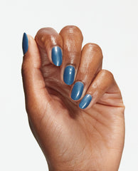 Hand with neatly manicured nails painted in Suzi Takes a Sound Bath, a glossy medium-blue OPI nail polish nail lacquer shade, held against a clean white background to showcase smooth, even color coverage and shine.