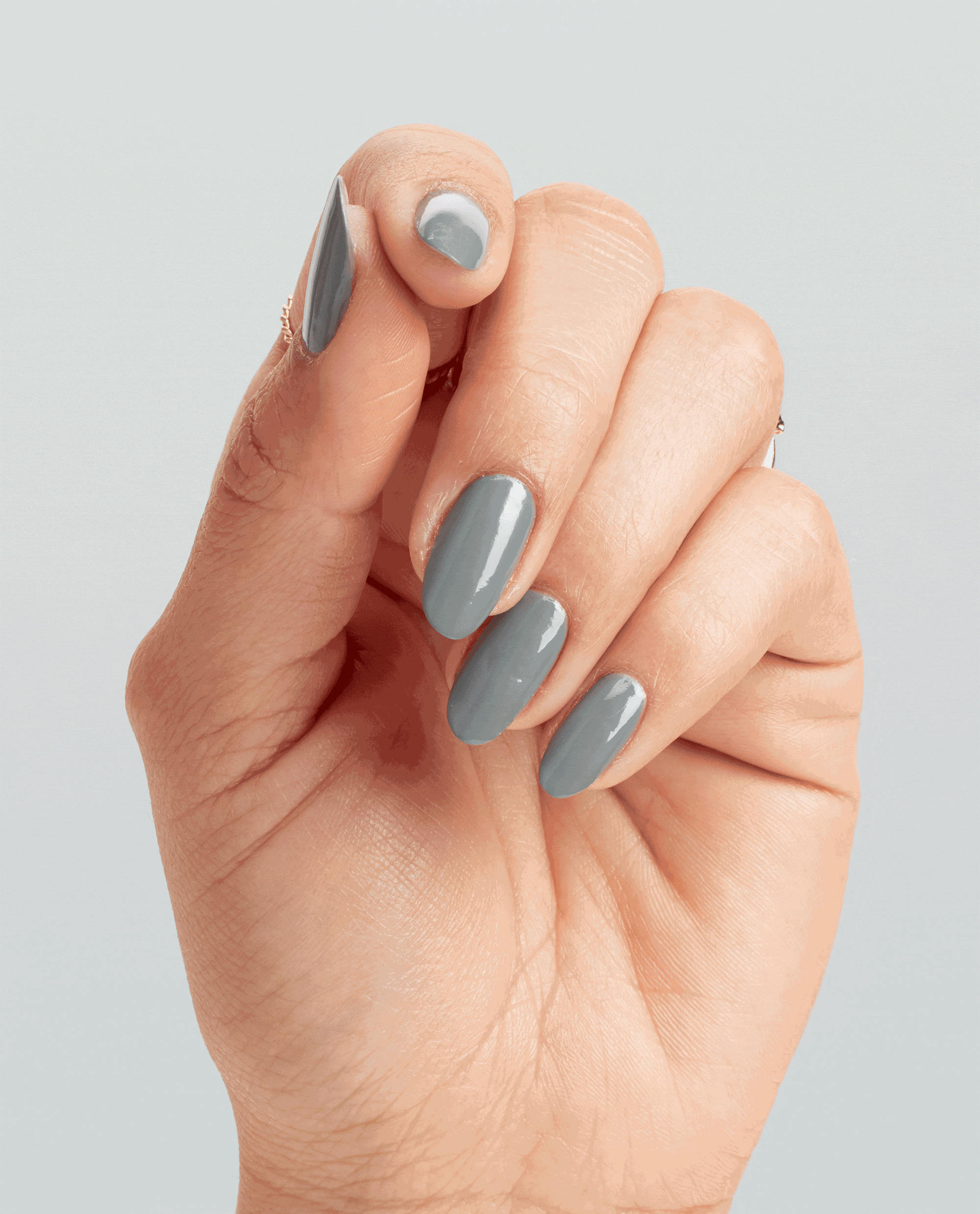 Hand with neatly manicured oval nails painted in Suzi Talks with Her Hands, a cool slate gray OPI nail polish shade, subtly moving against a soft light gray background to showcase the glossy nail lacquer finish.