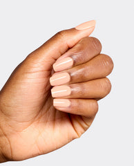 Hand modeling glossy, soft peach nude nails in OPI Suzi Take a Vow dipping powder, a subtle neutral shade for fall nail colors on a clean light gray background.