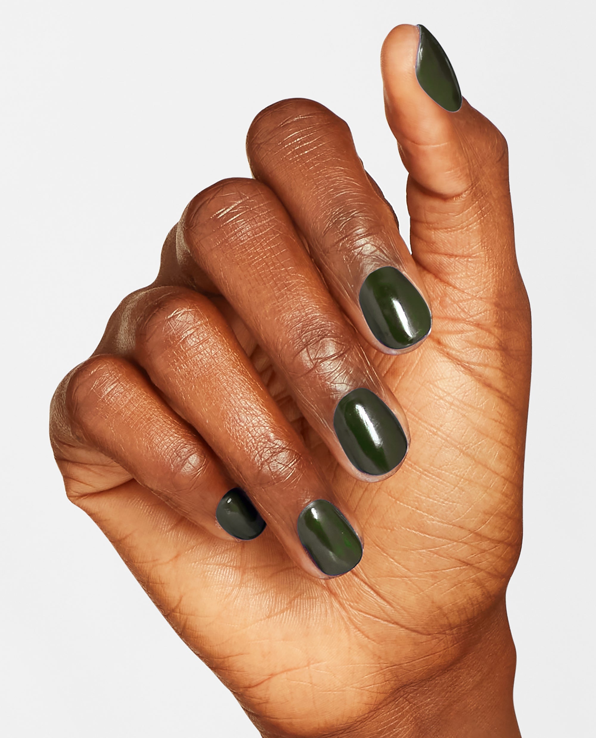 Hand with short, neatly manicured nails painted in Things I’ve Seen in Aber-green, a deep glossy forest shade of OPI nail polish nail lacquer, shown against a clean white background to highlight the rich green color and smooth finish.