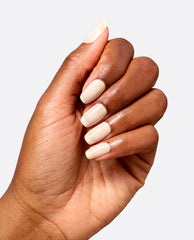Hand displays glossy almond-shaped nails painted with OPI Throw Me a Wink gel nail polish, a creamy soft ivory shade for elegant fall nail colors on a light gray background.