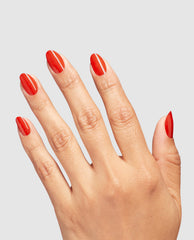 Hand modeling glossy red almond nails painted with Totally Red-ical OPI nail lacquer, a bold choice for fall nail colors, against a light gray studio background.