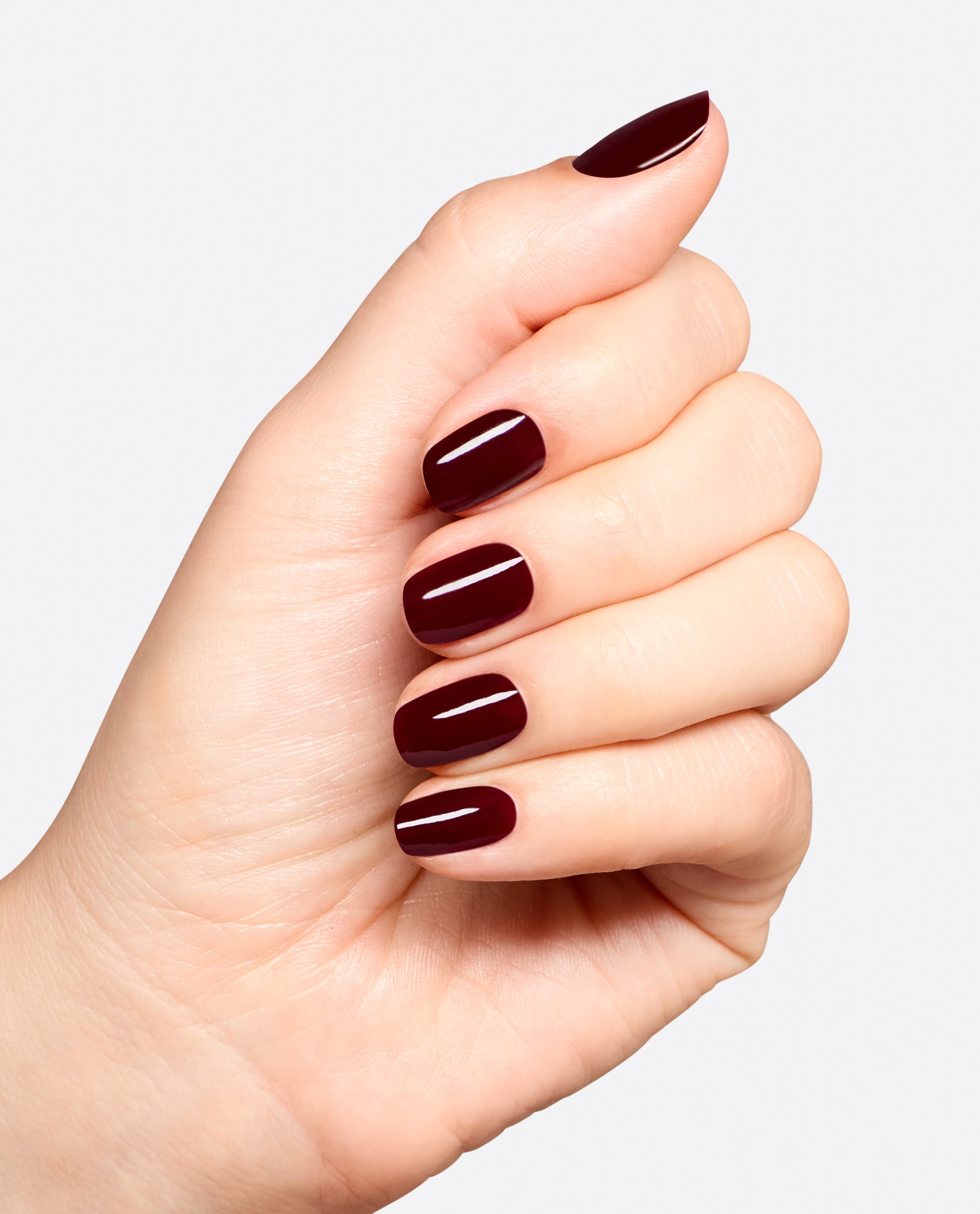 Hand displaying glossy deep burgundy manicure with Vampire State Building gel nail polish by OPI, a rich wine shade ideal for fall nail colors on a clean white background.