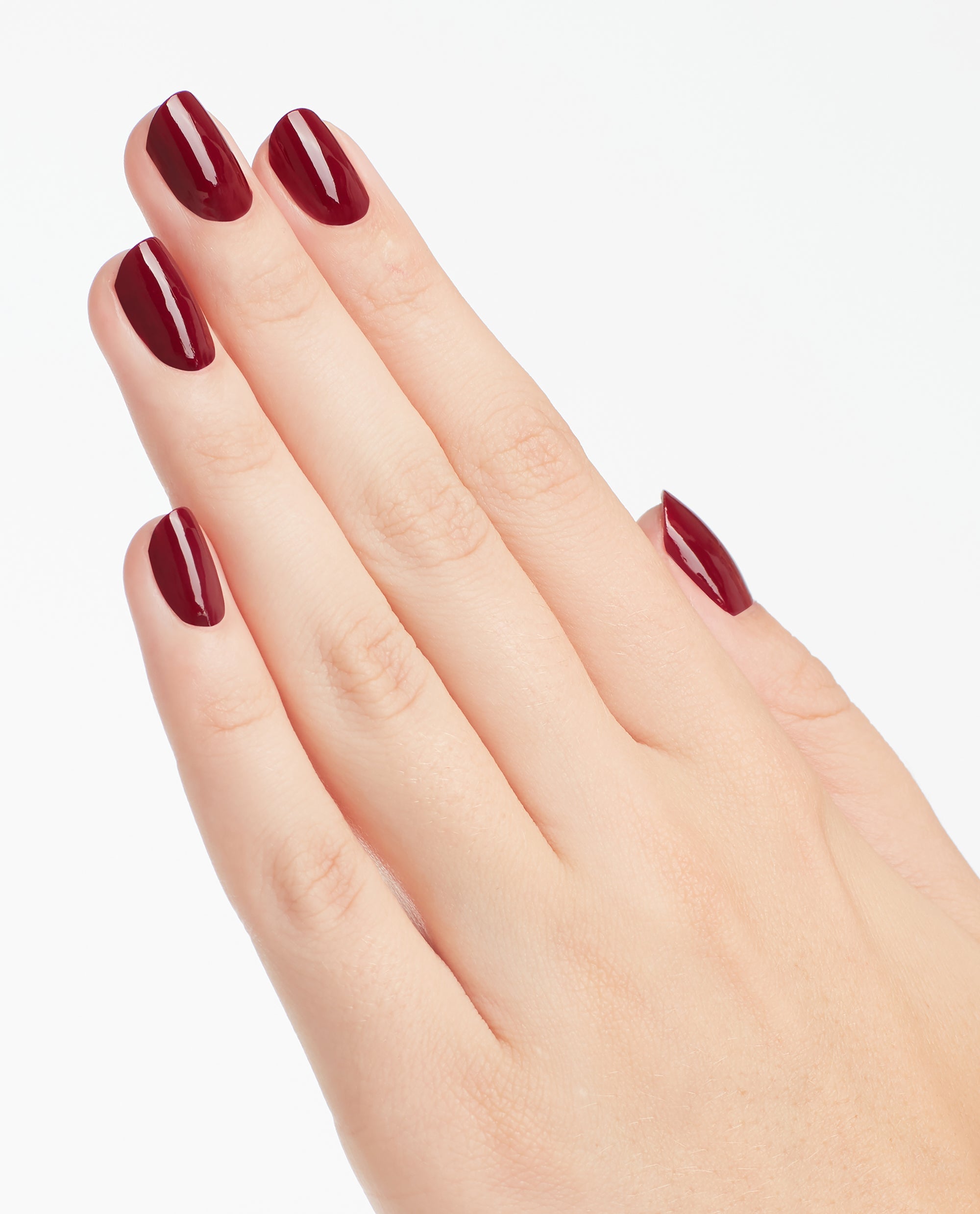 Hand modeling glossy deep burgundy OPI We the Female Nail Lacquer on short rounded nails, showcasing a rich shade for fall nail colors against a clean white background.